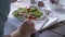 Detail of person eating mixed salad with grilled meat. Hands close-up handheld.