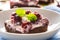 Detail of a piece of brownie with a cream, cherries and fresh mint leaves on a plate