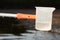 Detail of plastic sampling beaker on rod with sample of water