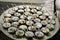 Detail of a plate full of small glasses with mussels with allioli and parsley during a catering. Concept food, wedding, menu,
