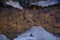 Detail of polluted stream bed. Polluted lifeless stream. Nature pollution concept. Stream in winter with ice around the edges. Top