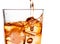 Detail of pouring scotch whiskey in glass with ice cubes on white