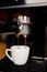 Detail of a professional coffe maker dripping coffe into an empty cup in a cafeteria