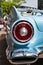 Detail of the rear fender and tail light of a sky blue Ford Fairlane convertible