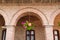 Detail of red vintage brick arcades, brown windows frame and hanging geranium flower pot