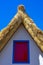 Detail of the roof, red window and blue frame of a typical house in the parish of Santana, Madeira Island.
