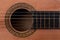 Detail of rosette decal, soundhole and strings on acoustic guitar