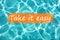 Detail of sentence `Take it easy` on swimming pool water and sun reflecting on the surface