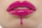 Detail shot of pink lipgloss dripping from woman\'s lips