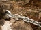 Detail of steel bolt anchor eye in sandstone rock hold steel chain.