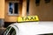 Detail of a TAXI sign on a roof of bright car