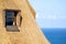 Detail of a thatched roof house using reed grass as building material. Windows visible and the ocean in the background.