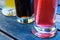 Detail of three glasses with chilled summer fruit drinks standing on blue painted wood.