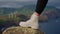 Detail of touristic boots. Unrecognizable adventurous female hiker climbing rocky mountains