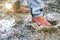 Detail of trekking boots in a mud. Muddy hiking boots and splash of water. Man splashing in muddy and water in the countryside.