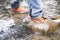 Detail of trekking boots in a mud. Muddy hiking boots and splash of water. Man splashing in muddy and water in the countryside.