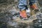 Detail of trekking boots in a mud. Muddy hiking boots and splash of water. Man splashing in muddy and water in the countryside.