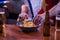 Detail of two man`s hands taking chips from a bowl with beers next to them, at the living room table of two friends watching