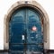 Detail view of a large blue arched wooden doorway with a sign in French saying