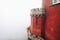 Detail view of a red dome column at Pena Palace Palacio da Pena fully engulfed in fog with poor views of the nearby forest