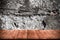 Detail of a wall of an ancient stone house. View from dark wooden gangway, table or bridge. Toned