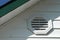Detail of white aluminum siding, white vinyl vent, white soffit and dark green fascia