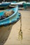 Detail of a white and blue fishing boat on the beach. old rope on the prow