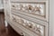 Detail of white drawer carving. abstract background. furniture in classic style. white tree with gold trim. patina. carving. small