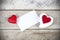 Detail of white empty card with two heart symbols on wooden table as background