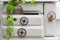 Detail of white miniature cupboard with toothed wheels as drawer knobs