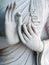 Detail of a white statue of the Buddha with his hands. Fingers in mudra