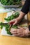 Detail of woman cutting the center spine from a curly kale leaf