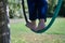 Detail of a woman`s feet on an aero hoop hanging from a tree branch in the middle of a park. Foot concept, aerial hoop, pole danc