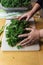 Detail of woman`s hands gathering freshly chopped kale on a cutting board in order to massage it