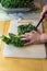 Detail of a woman using a knife to slice down the side of the rib on a kale leaf