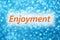 Detail of word `Enjoyment` on a shiny blurred blue background