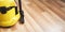 Detail of yellow vacuum cleaner machine on wooden laminated floor - space for text right side