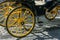 Detail of yellow wheel of horse carriage on a cobblestone street