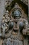 Detailed carvings of deity with ornaments and weapons at Somnathpur, Karnataka, India.