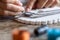 Detailed macro close-up of woman fingers working on a handmade knotted micro macrame bracelet with blurred spools of thread in