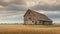 A detailed photograph of a rustic, weathered barn in a vast open field