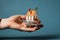 Detailed shot hand with miniature shopping cart, paper house, and keys