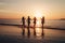 A detailed silhouettes of a group of friends running towards the sea on a beautiful beach at sunset