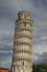 Detailed view of ancient Leaning Tower of Pisa against stormy sky and gloomy clouds. Notable landmark of Pisa