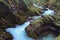 Detailed view of fast winding stream with turquoise water between big stones covered by moss in famous Vintgar Gorge