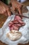 Detailed view of a hand slicing homemade pork chorizo on wooden table