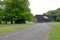 Detailed view of a large wooden barn and driveway, leading to out of view professional horse racing stables and stud
