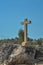 Detailed view at the stone crucifix sculpture, blue sky and field of trees on background