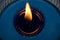 Details of a burning blue candle on a glass container