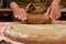 Details: chef confectioners hands using rolling pin, roll out the dough on a floured wooden board. Baking concept.